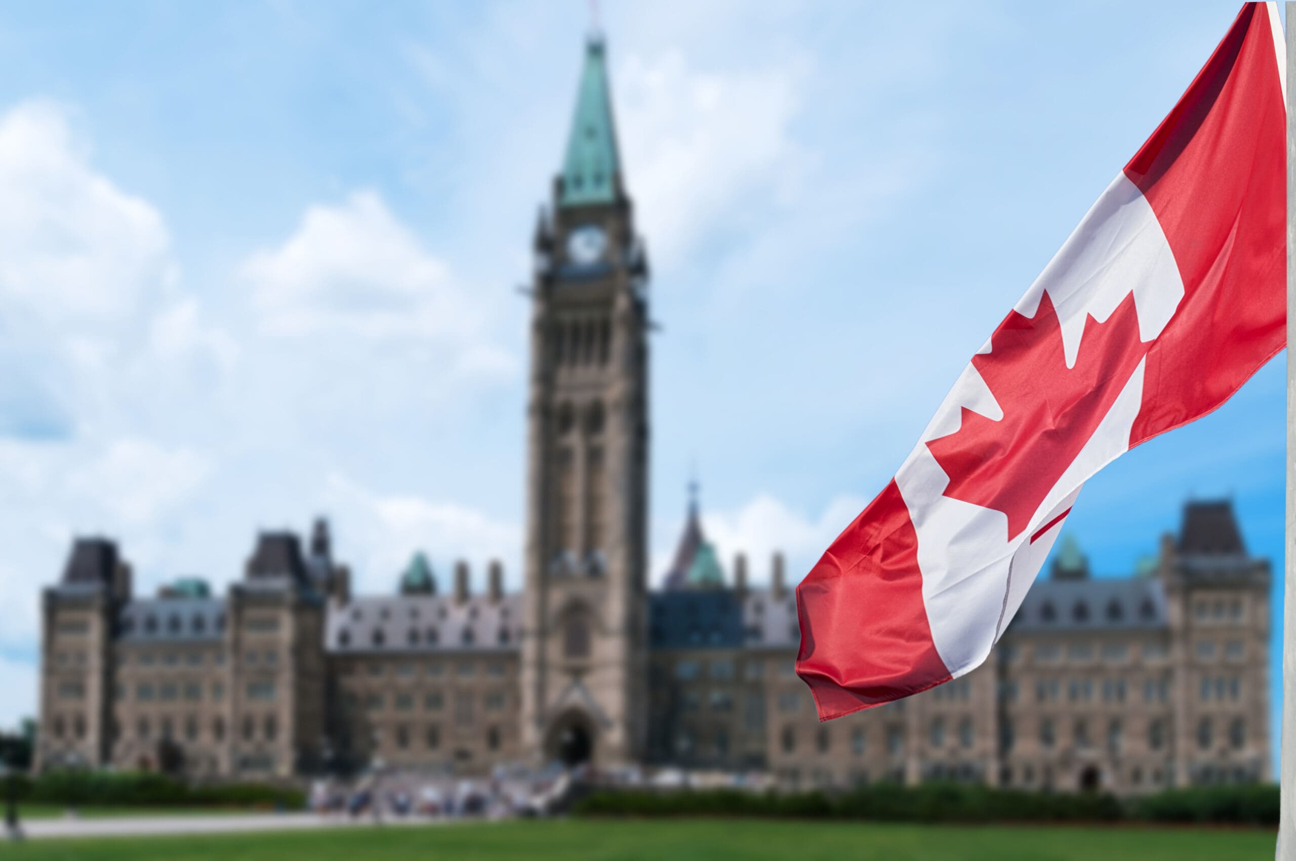 Canadian flag waving with Parliament Buildings hill in the background Ottawa,Ontario, Canada